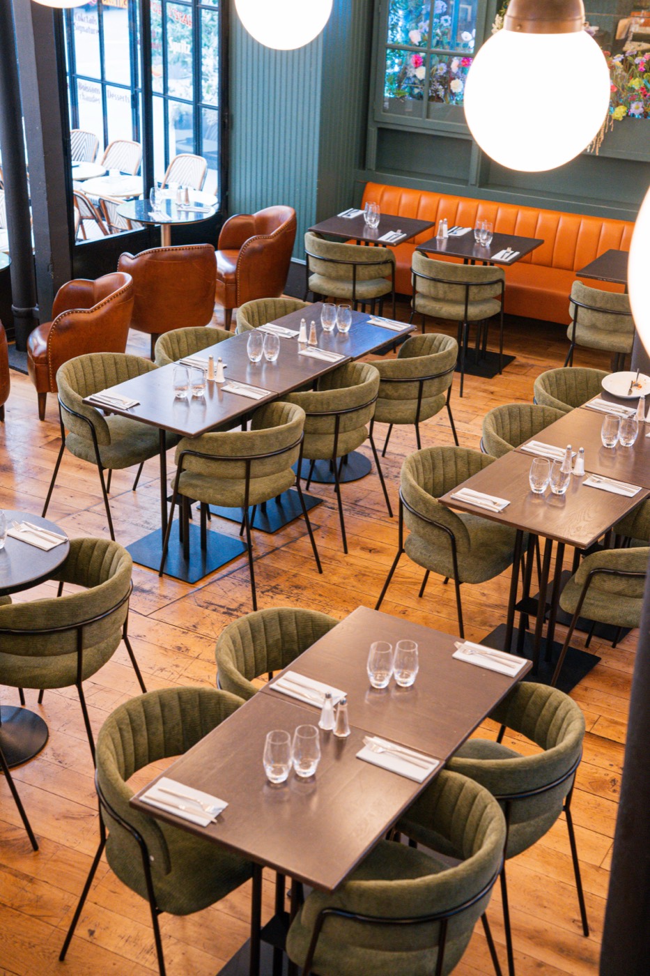 Salle du Bistrot Jad vue de haut : chaises en velours vert, banquette orange et parquet chêne